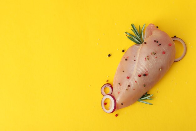 Filé de frango cru com especiarias em fundo amarelo