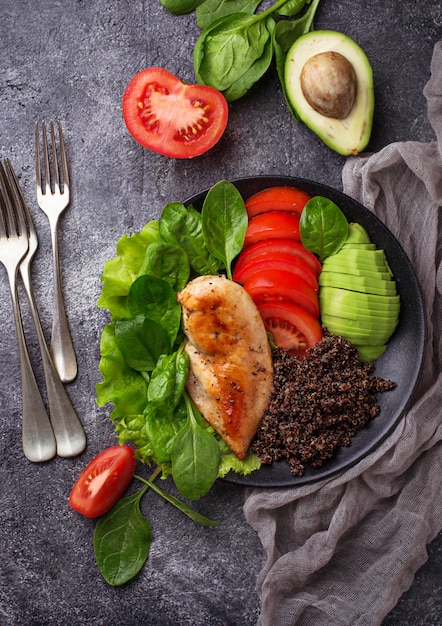 Filé de frango grelhado com quinoa preta, salada, tomate e abacate. comida equilibrada e saudável