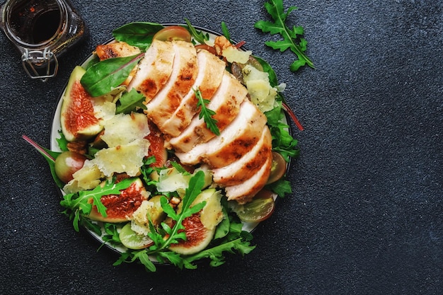 Filé de frango grelhado com rúcula de uva de figo e salada de acelga Vista superior do fundo da mesa preta