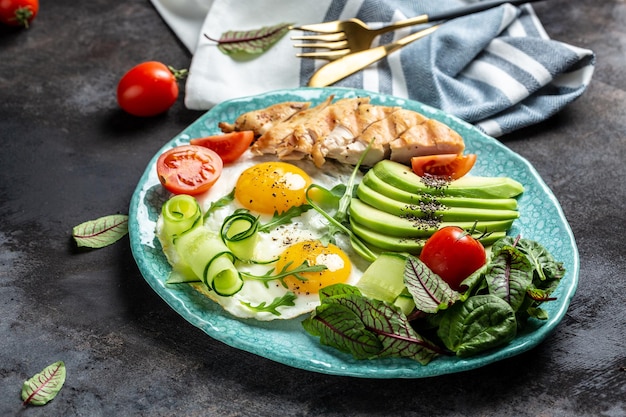 Filé de frango grelhado com salada tomates frescos pepinos ovos e abacate Café da manhã saudável dieta cetogênica conceito de almoço lugar para vista superior do texto
