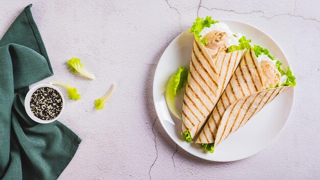 Foto filé de frango grelhado embrulhado em tortilha com alface e molho em um prato