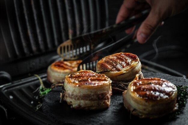 Filé de Mignon Grelhado Lombo de Carne Filé de Bifes de Carne Envolto em Bacon. Cozinhar bife na grelha pelas mãos do chef.