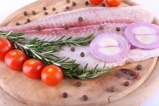 Filé de Pangasius na tábua de madeira com tomate cereja e especiarias em fundo qhite