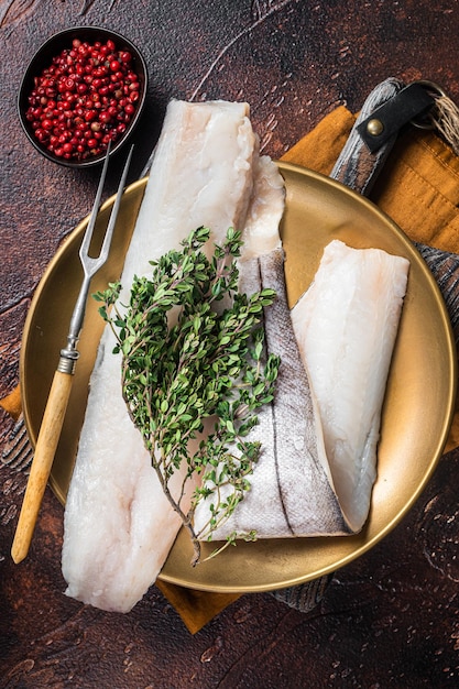 Filé de peixe branco arinca crua no prato com alecrim e tomilho Fundo escuro Vista superior