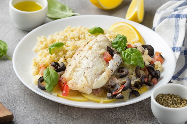 Filé de peixe branco assado com azeitonas, tomate e limão