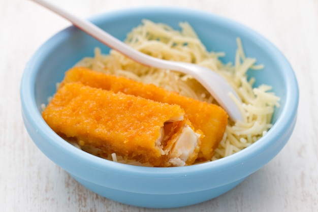 Filé de peixe com macarrão em uma tigela azul sobre fundo branco de madeira