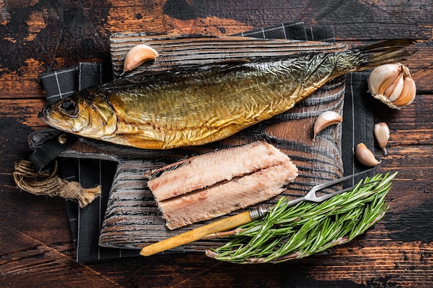 Filé de peixe de arenque defumado perfumado na placa de madeira com ervas fundo de madeira vista superior