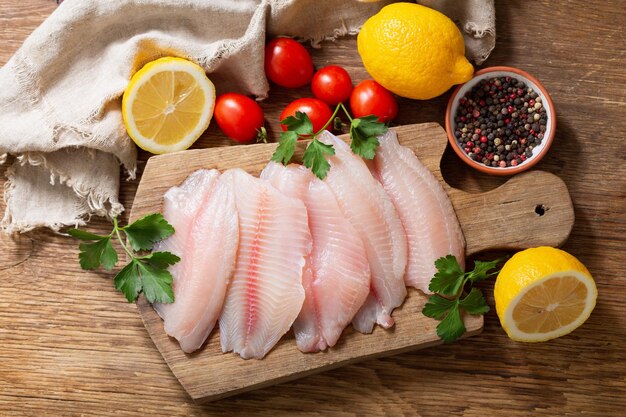 Filé de peixe fresco de tilápia com ingredientes para cozinhar vista superior