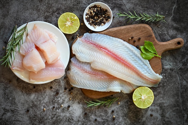 Filé de peixe na placa de madeira com ingredientes para cozinhar filé de peixe pangasius cru fresco com ervas e especiarias pimenta preta limão limão carne boneca peixe tilápia listrado peixe-gato