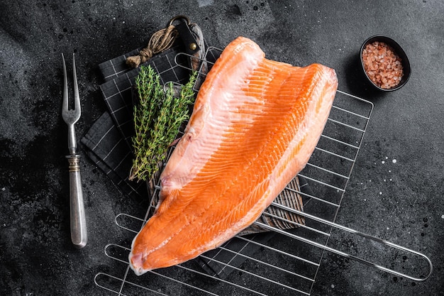 Filé de peixe salmão cru cozinhando bifes na grelha com ervas Fundo preto Vista superior