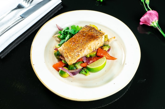 Filé de poleiro em molho doce picante em um travesseiro de legumes cozidos no prato amarelo no escuro. comida saborosa e saudável. serviço de restaurante. foto de comida para receita ou menu