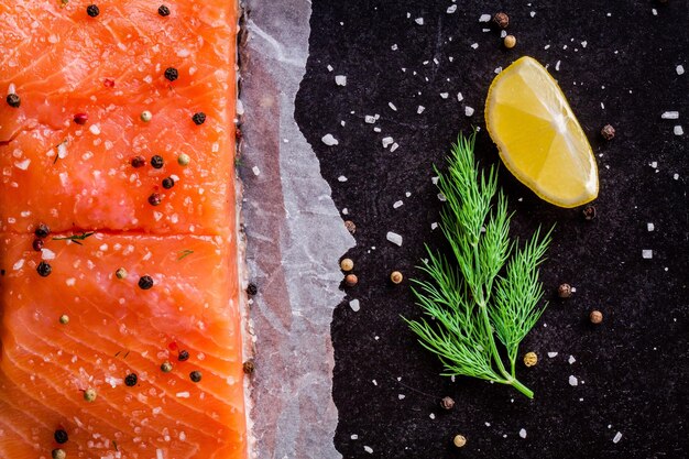 Filé de salmão fresco com endro e limão em fundo escuro