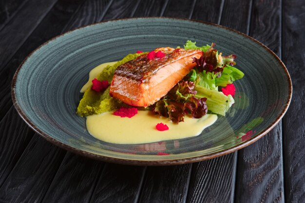 Filé de salmão frito com folhas de salada e molho de creme decorado com caviar