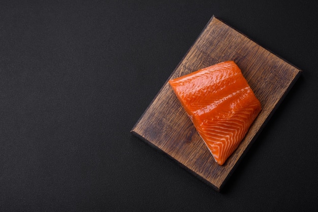 Filé de salmão vermelho cru com especiarias salgadas e ervas em um fundo escuro de concreto