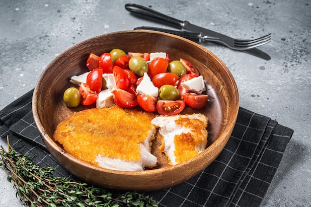 Filé de tilápia frito em um prato com salada Fundo cinza Vista superior