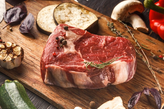 Filé mignon cru. Carne bovina fresca, alecrim na placa de madeira em fundo preto. Ingredientes orgânicos para refeições em restaurantes, vegetais e especiarias