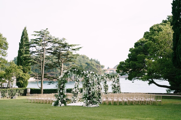 Fileira de arcos de casamento cercados por cadeiras em um gramado verde perto do mar