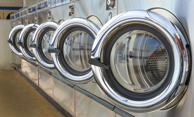 Fileira de máquinas industriais da lavanderia na lavagem automática.