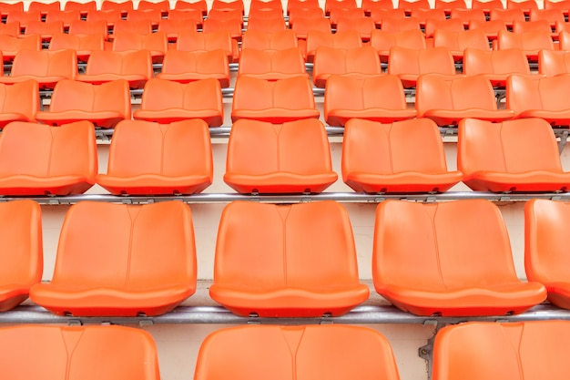 Fileiras de assentos plásticos alaranjados vazios da arquibancada no estádio.