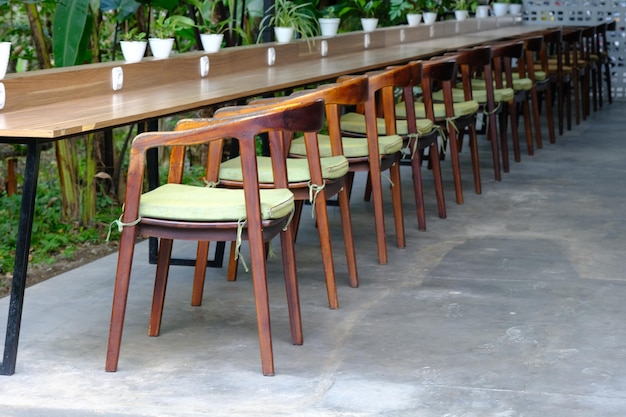fileiras de cadeiras e mesas de madeira em um jardim tropical. local de trabalho ao ar livre. relaxamento. Meja kursi.
