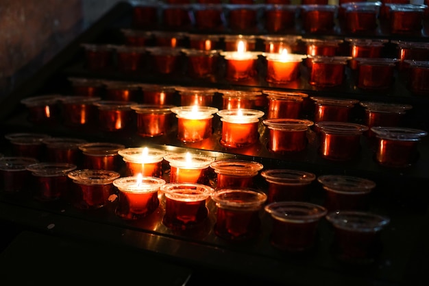 Fileiras de velas acesas em uma igreja escura