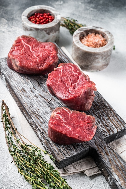 Filet Mignon Beef rohe Steaks auf einem Holzbrett mit Salz und Pfeffer. Weißer Hintergrund. Ansicht von oben.