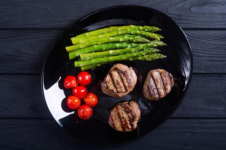 Filet mignon a la parrilla con espárragos y tomates Sreak de ternera sobre fondo rústico