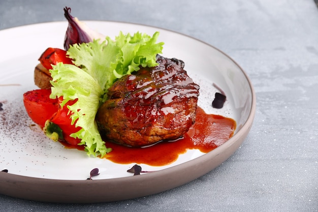 Filet mignon a la plancha de cerca con verduras en la mesa de hormigón.