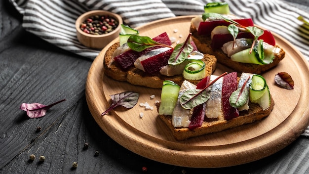 Filete de arenque Sándwich con rodaja de arenque salado remolacha pepino verde cebolla y microgreen en las tostadas Cocina escandinava Tradición danesa sándwich abierto vista superior