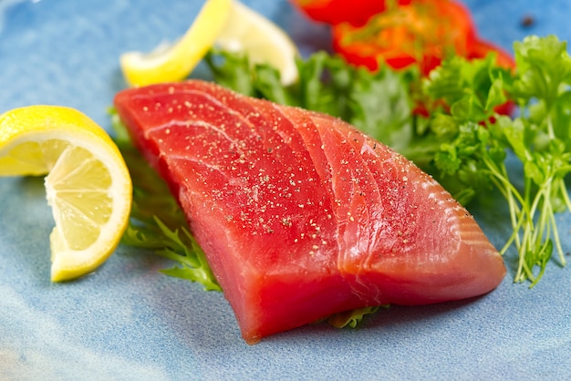 Filete de atún crudo con ensalada y limón en placa azul