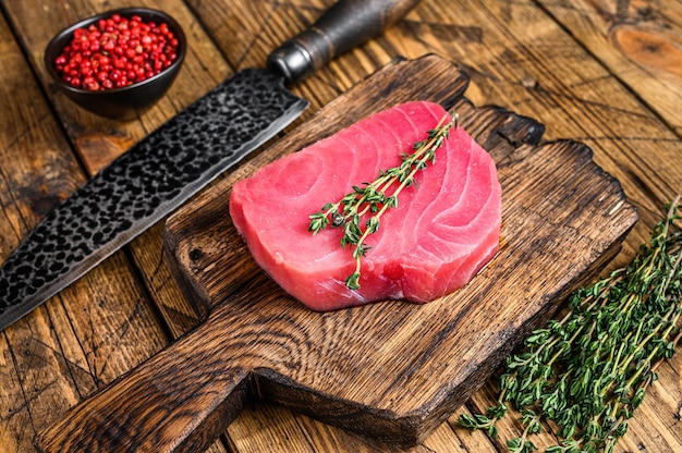 Filete de atún crudo fresco sobre una tabla de cortar de madera con un cuchillo