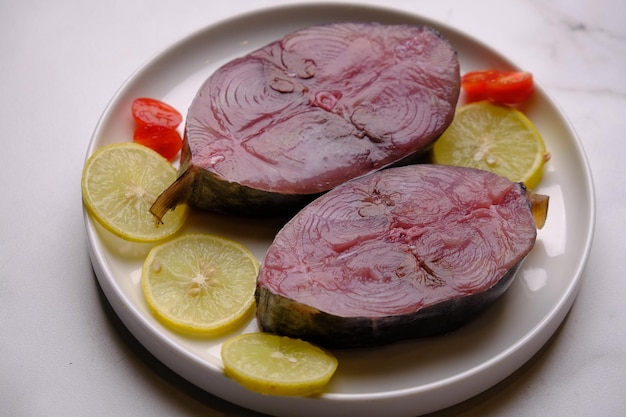 filete de atún en rodajas. filete de atún crudo en un cuenco de cerámica. rodajas de limón, tomates cherry. proteína animal.