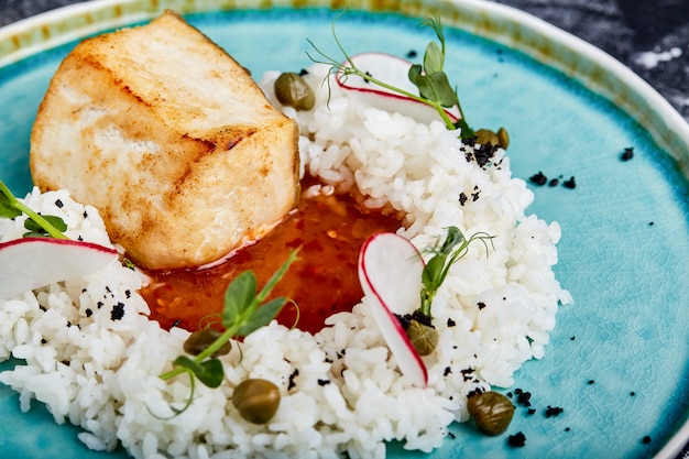 Filete de bacalao con arroz y salsa en un plato azul