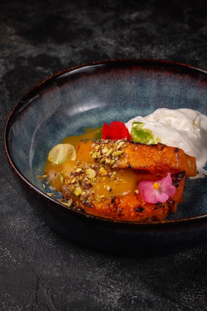 Filete de calabaza a la parrilla en una placa azul sobre una mesa oscura