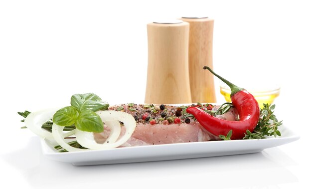 Filete de carne cruda con especias y hierbas en un plato aislado en blanco