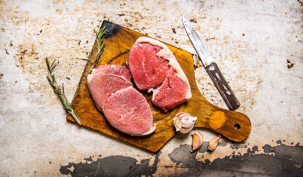 Filete de carne cruda fresca con especias sobre una tabla de madera