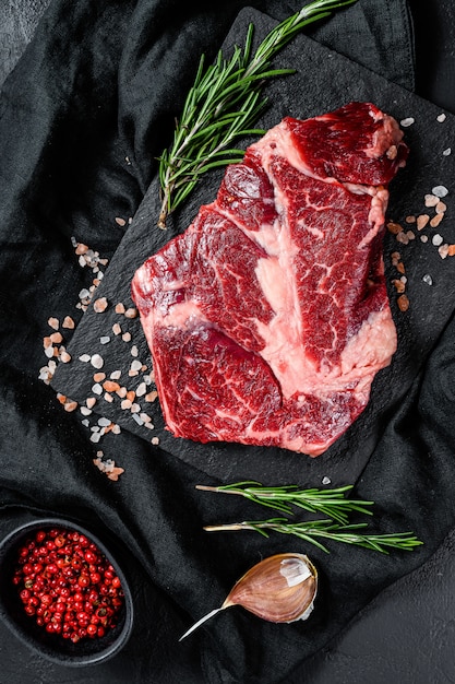 Filete de carne cruda en una tabla de cortar. Carne de granja ecológica. Fondo negro