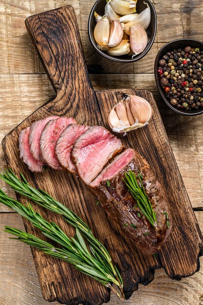 Filete de carne de filete de cordero en rodajas a la parrilla sobre una tabla para cortar