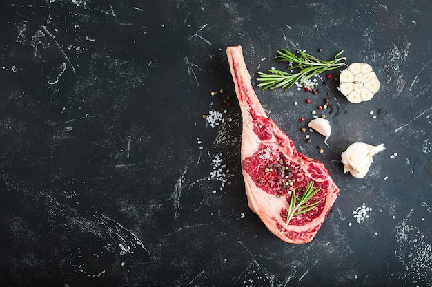 Filete de carne de mármol crudo, hierbas, condimentos, fondo de piedra rústica.