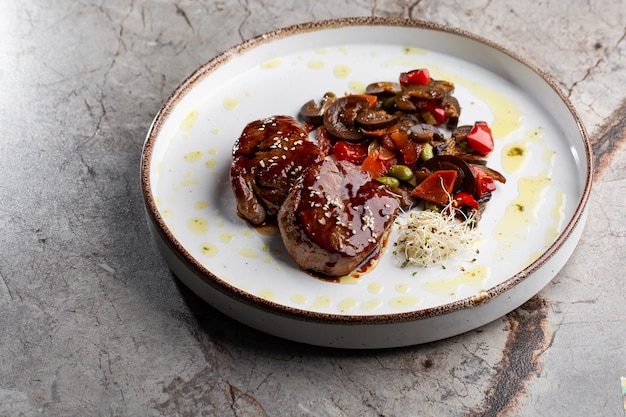 Filete de carne a la parrilla envuelto en medallones de tocino con salsa de frambuesa servido con vegetales y champiñones