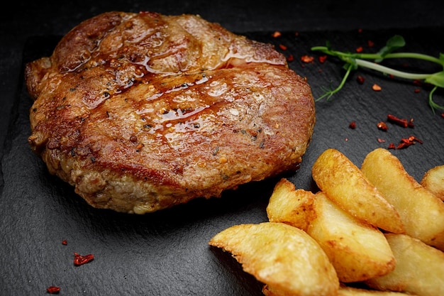 Filete de carne en una piedra negra con patatas fritas