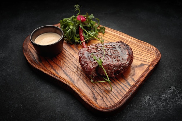 Filete de carne en la tabla de madera sobre un fondo oscuro