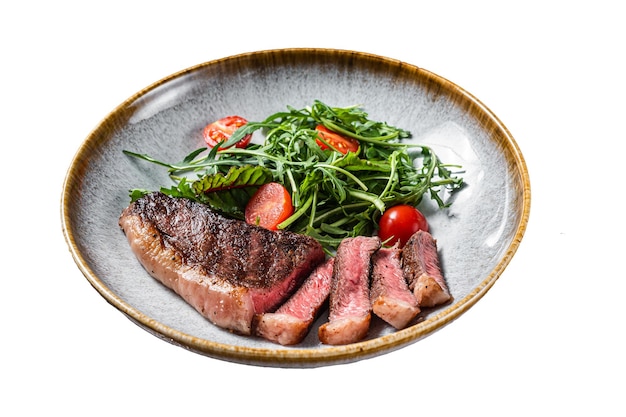 Filete de carne de ternera de solomillo a la parrilla en un plato con ensalada de verduras aislado de fondo blanco