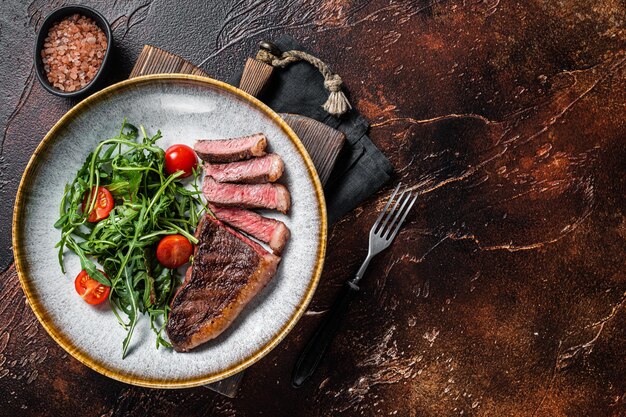 Filete de carne de ternera de solomillo a la parrilla en un plato con ensalada de verduras Fondo oscuro Vista superior Espacio de copia