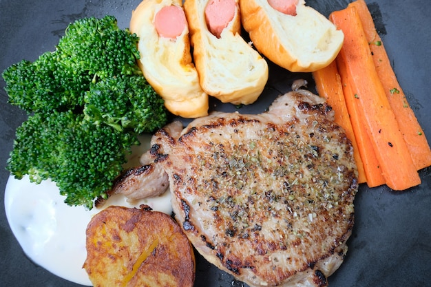 Foto filete de carne con verduras asadas y especias colocadas en un plato sobre una mesa de madera