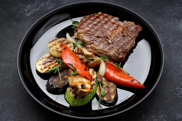 Filete de carne con verduras a la parrilla en un plato negro