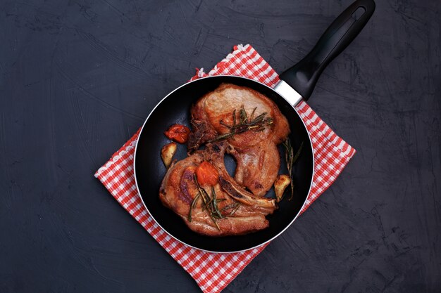 Filete de cerdo asado en sartén sobre fondo negro