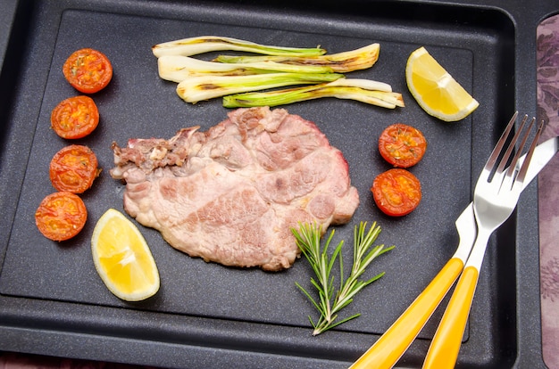 Filete de cerdo asado con tomate y verduras.