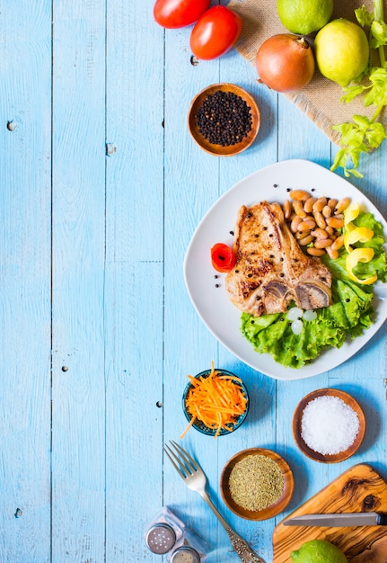 Foto filete de cerdo cocina casera con especias deja lechuga en tabla de cortar de madera y un plato