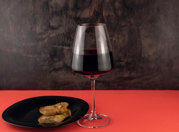 Filete de cerdo y una copa de vino tinto sobre un fondo rojo.
